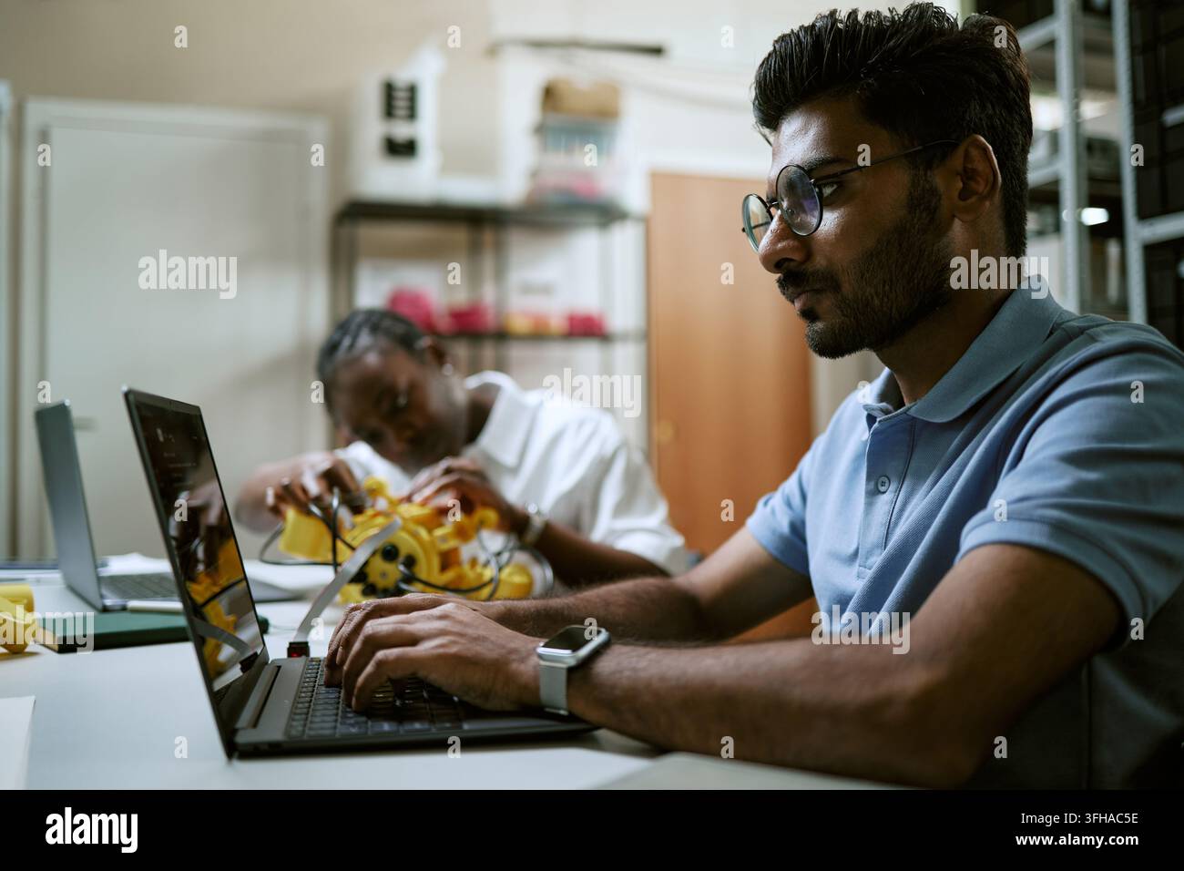 Indian Man Coding on Laptop during Robotics Engineering Workshop Stock Photo