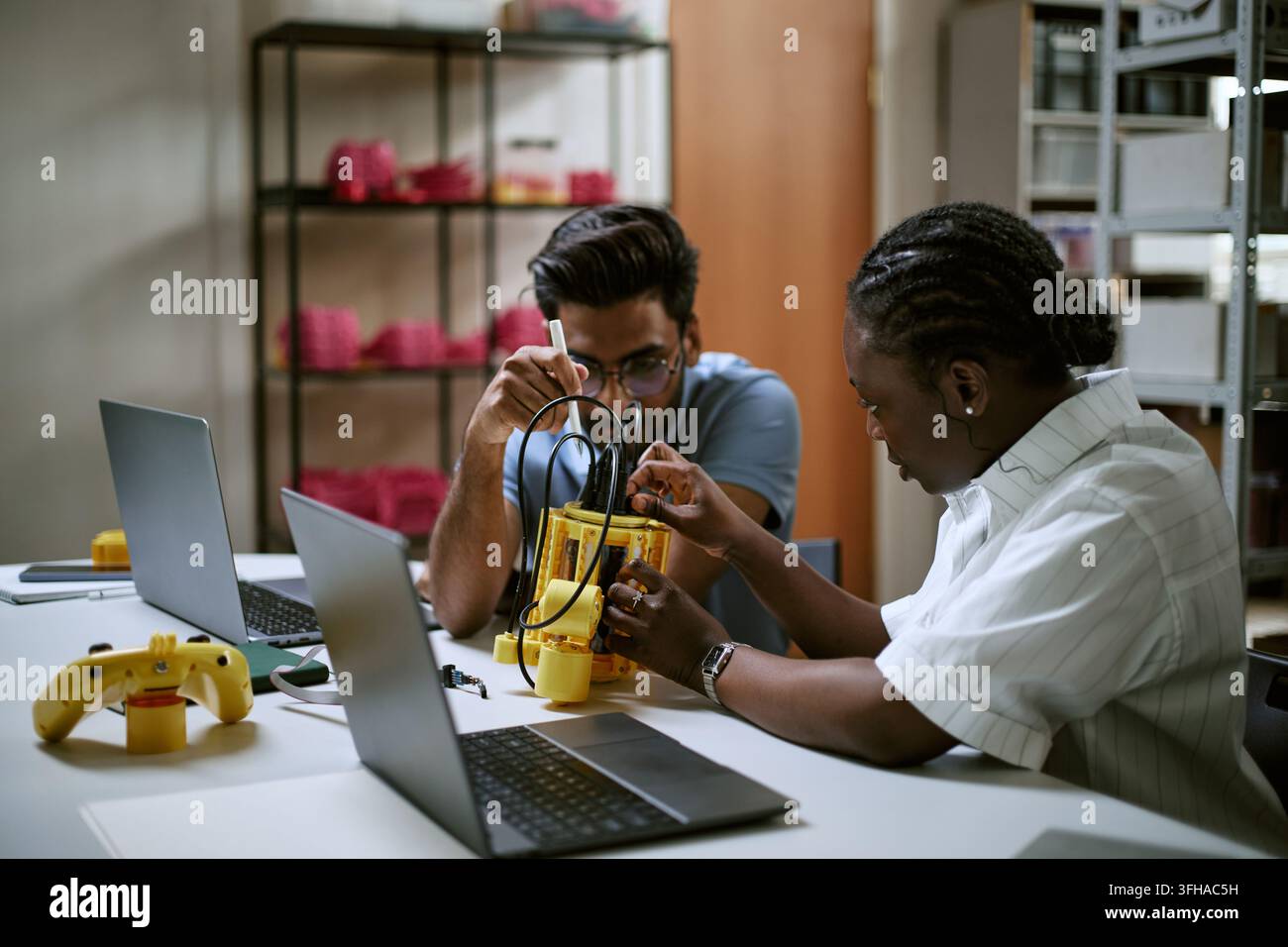 Multiethnic Engineers Assembling Robotic Device in Laboratory Stock Photo