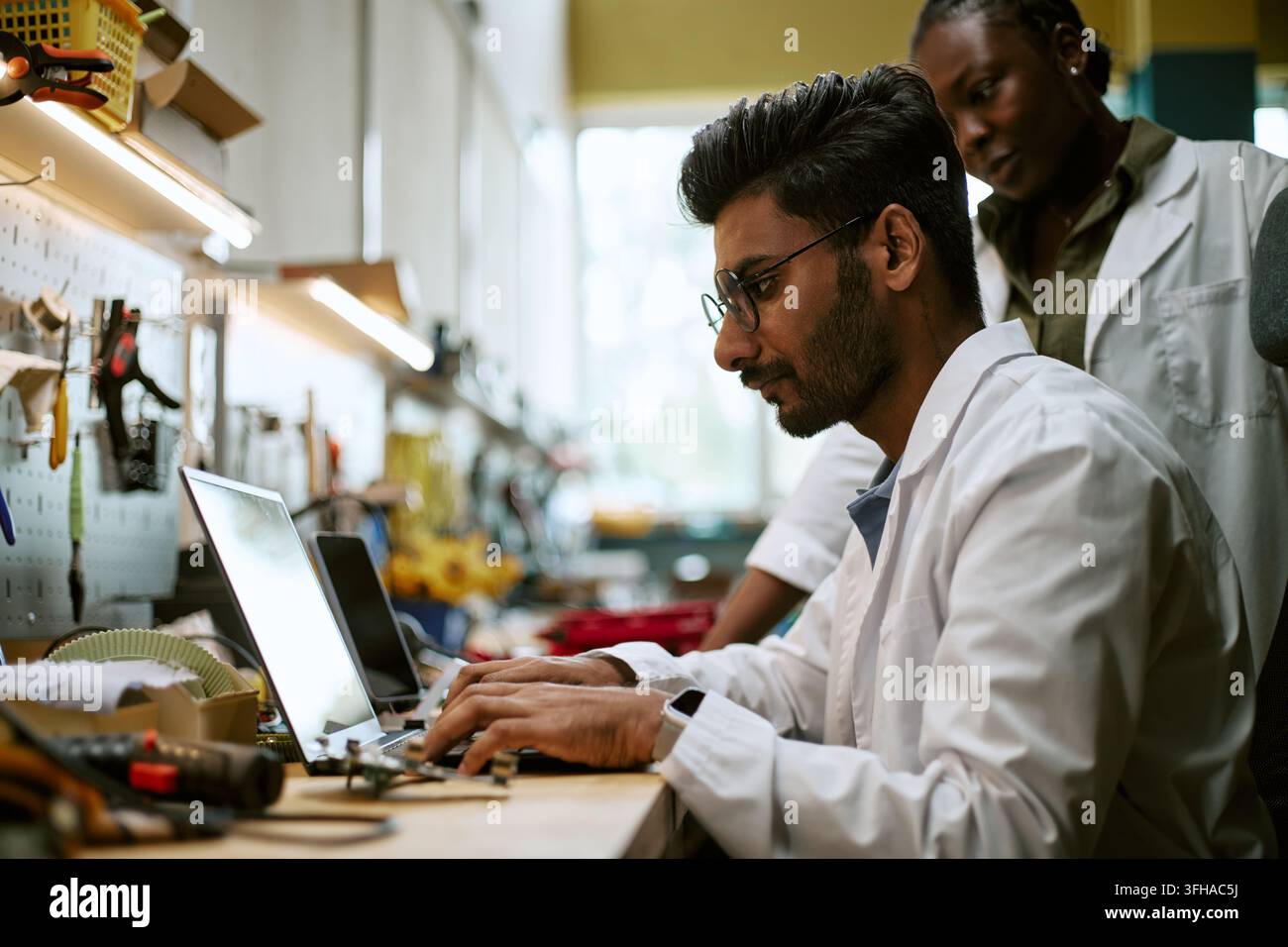 Diverse Engineers Working on Laptop in Robotics Laboratory Stock Photo