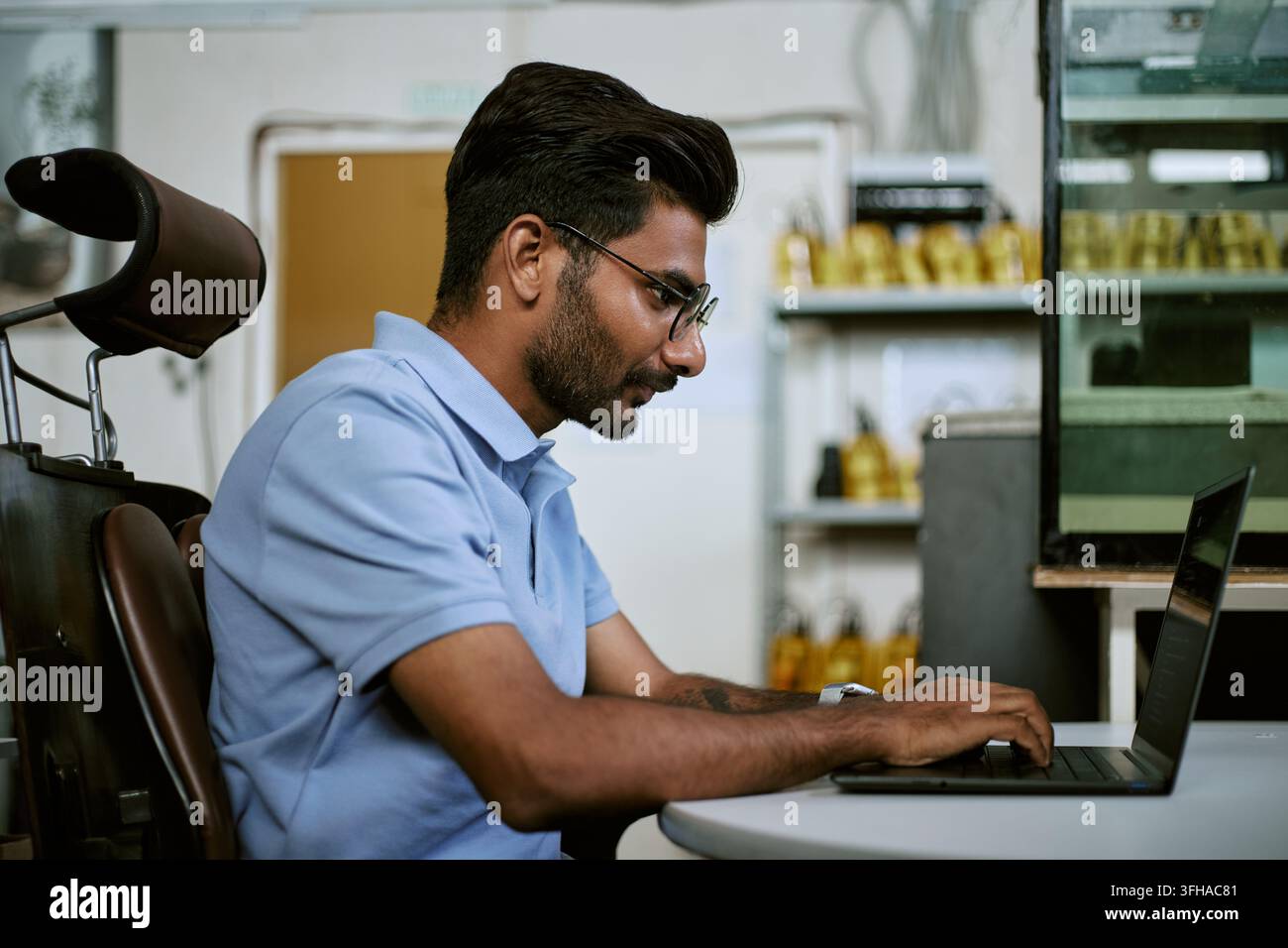 Indian Man Typing on Laptop Computer While Working in Modern Office Stock Photo