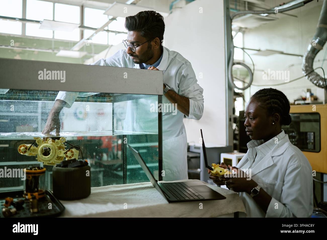 Diverse Engineers Testing Underwater Robot in Laboratory Tank Stock Photo