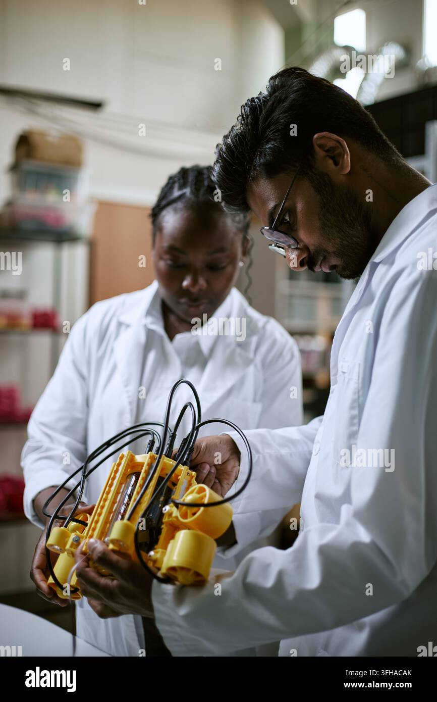 Multiethnic Engineers Assembling Robotic Device in Modern Lab Stock Photo