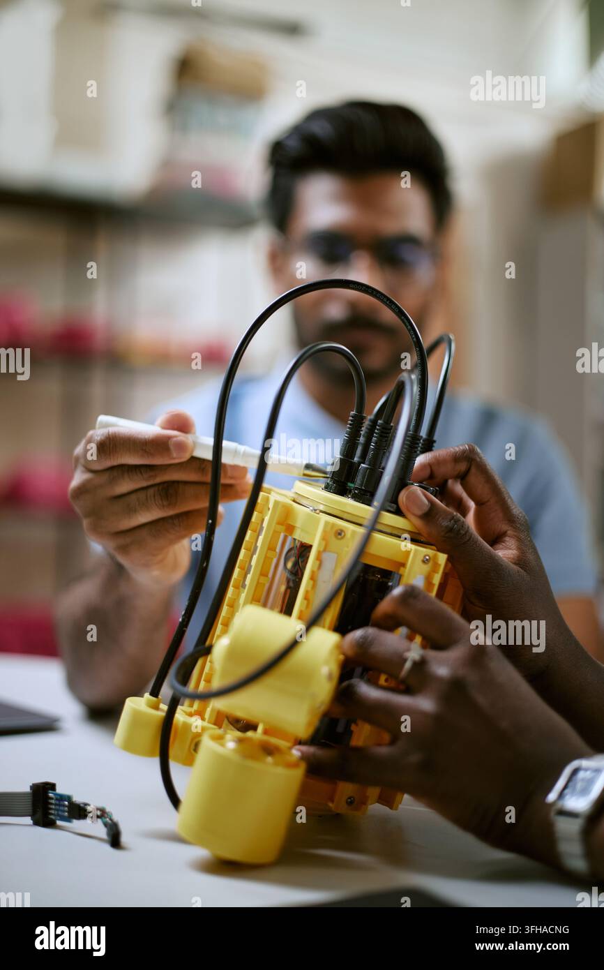 Diverse Engineers Assembling Robotic Prototype in Technology Lab Stock Photo