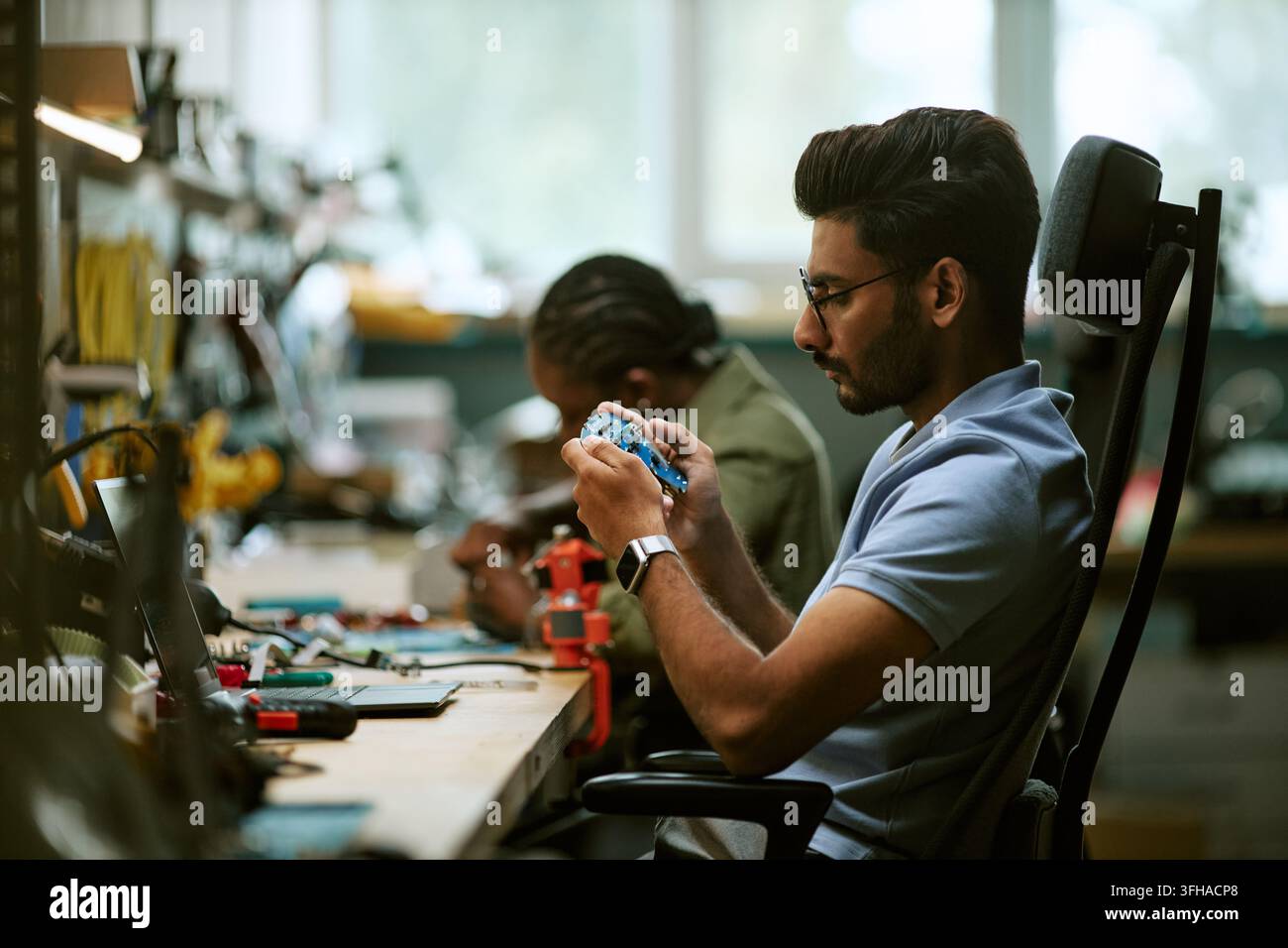 Indian Engineer Inspecting Circuit Board in Hardware Workshop Stock Photo