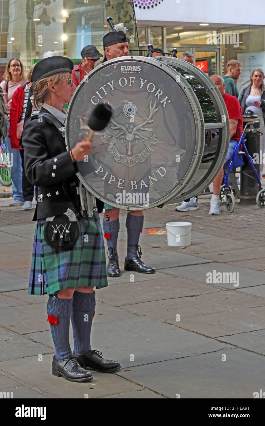 City of York Pipe Band bass drummer performs in York city centre, wearing traditional Scottish dress. Stock Photo