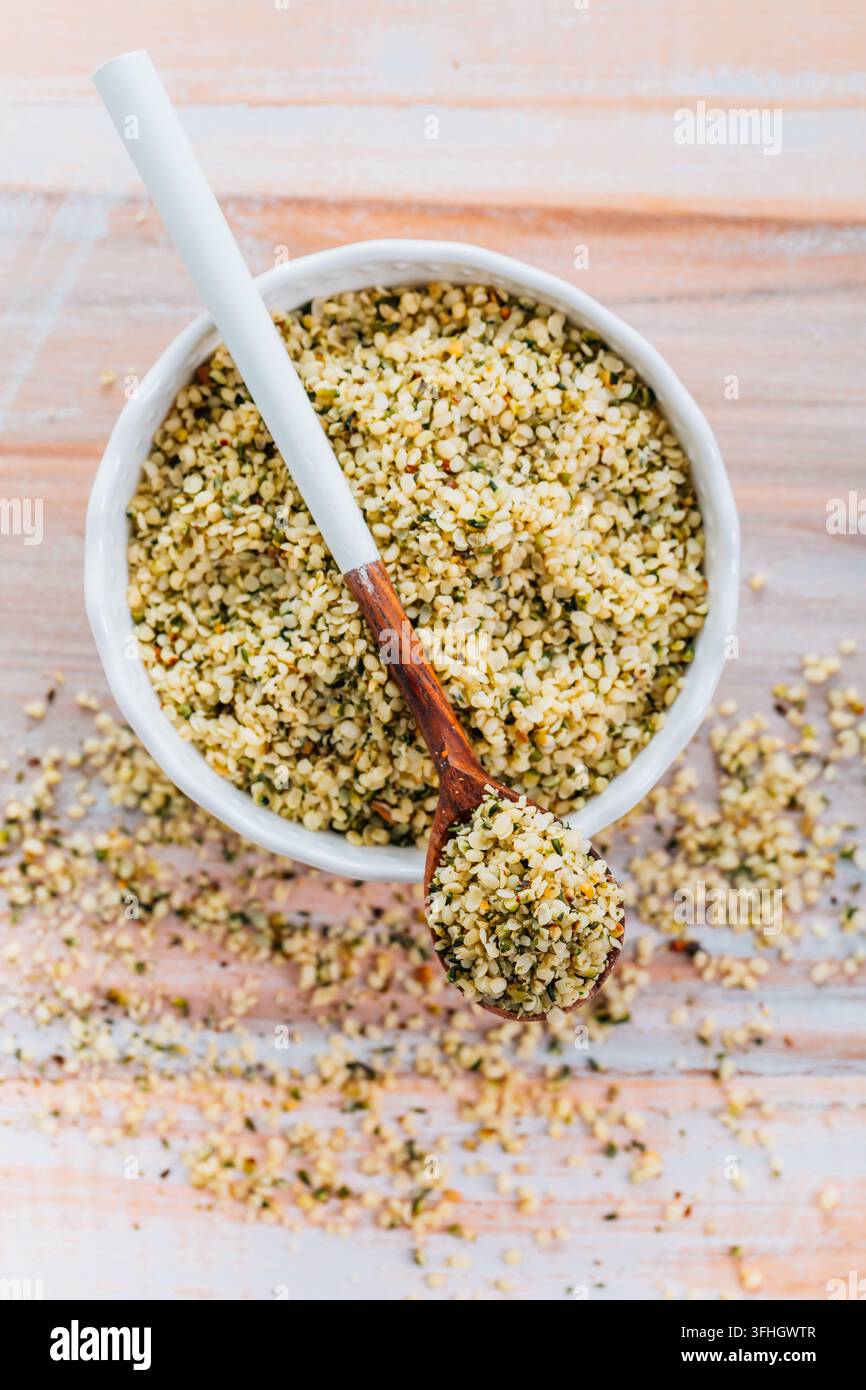 Nutritious hemp seeds in a white ceramic bowl with a wooden spoon Stock Photo