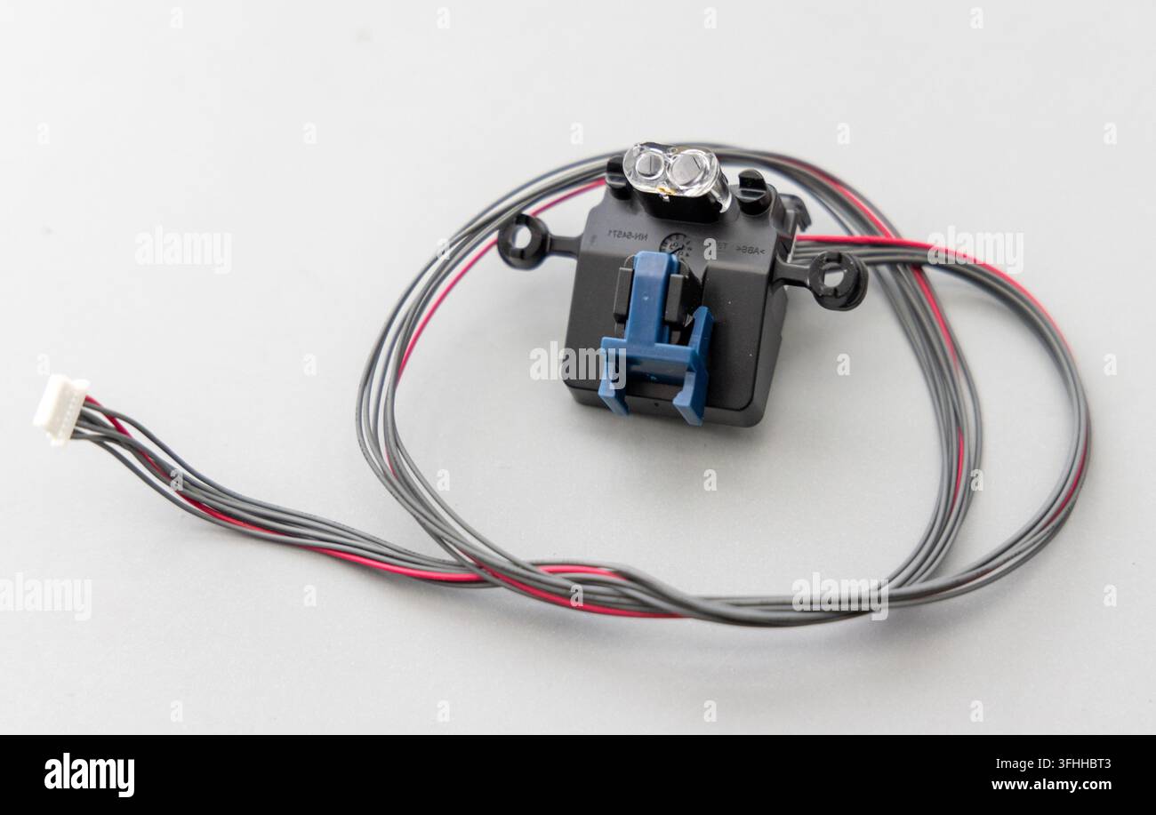 A black electronic sensor module with wires is on a gray surface Stock Photo