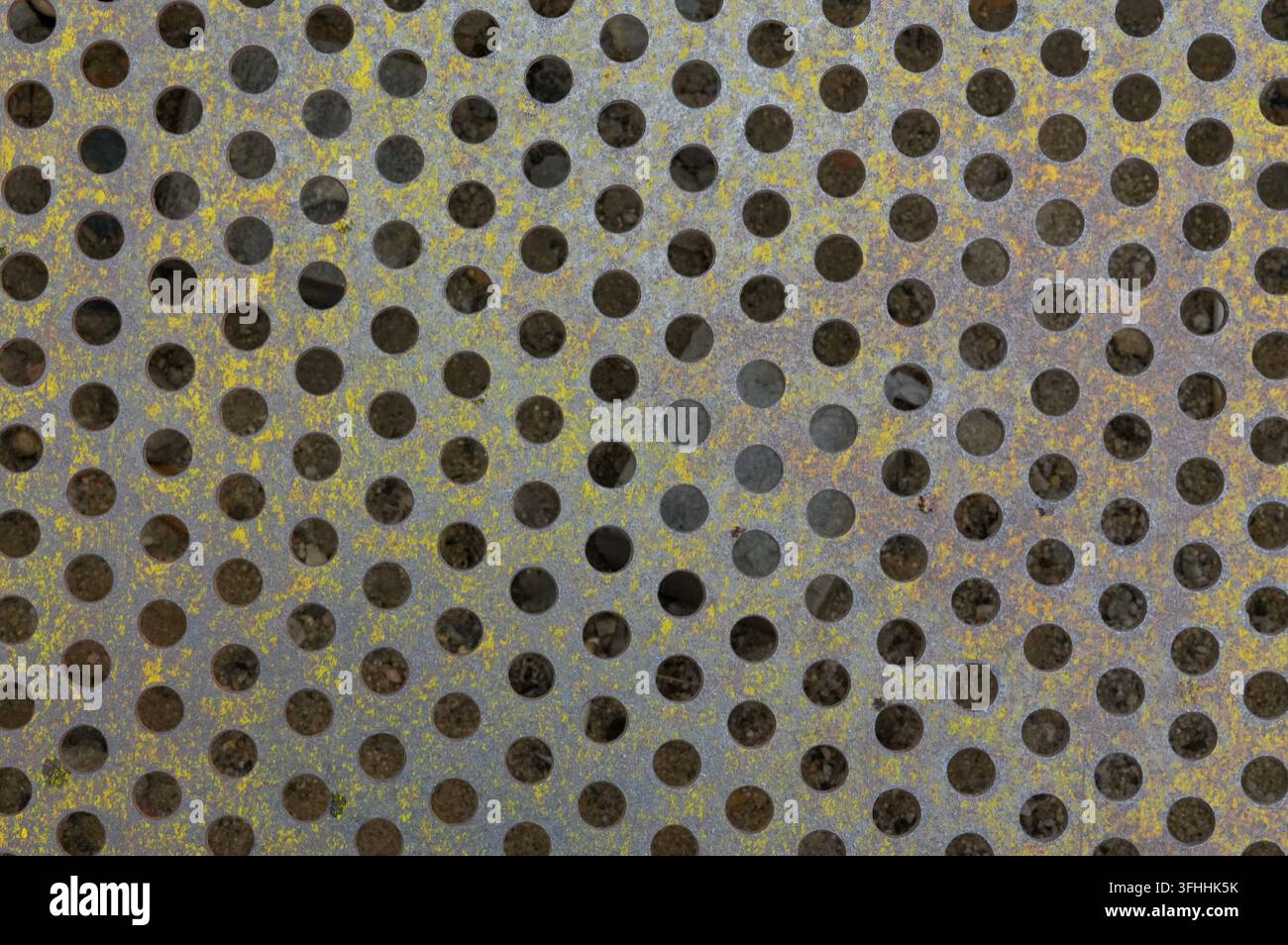 Rusty metal surface with uniform circular perforations Stock Photo