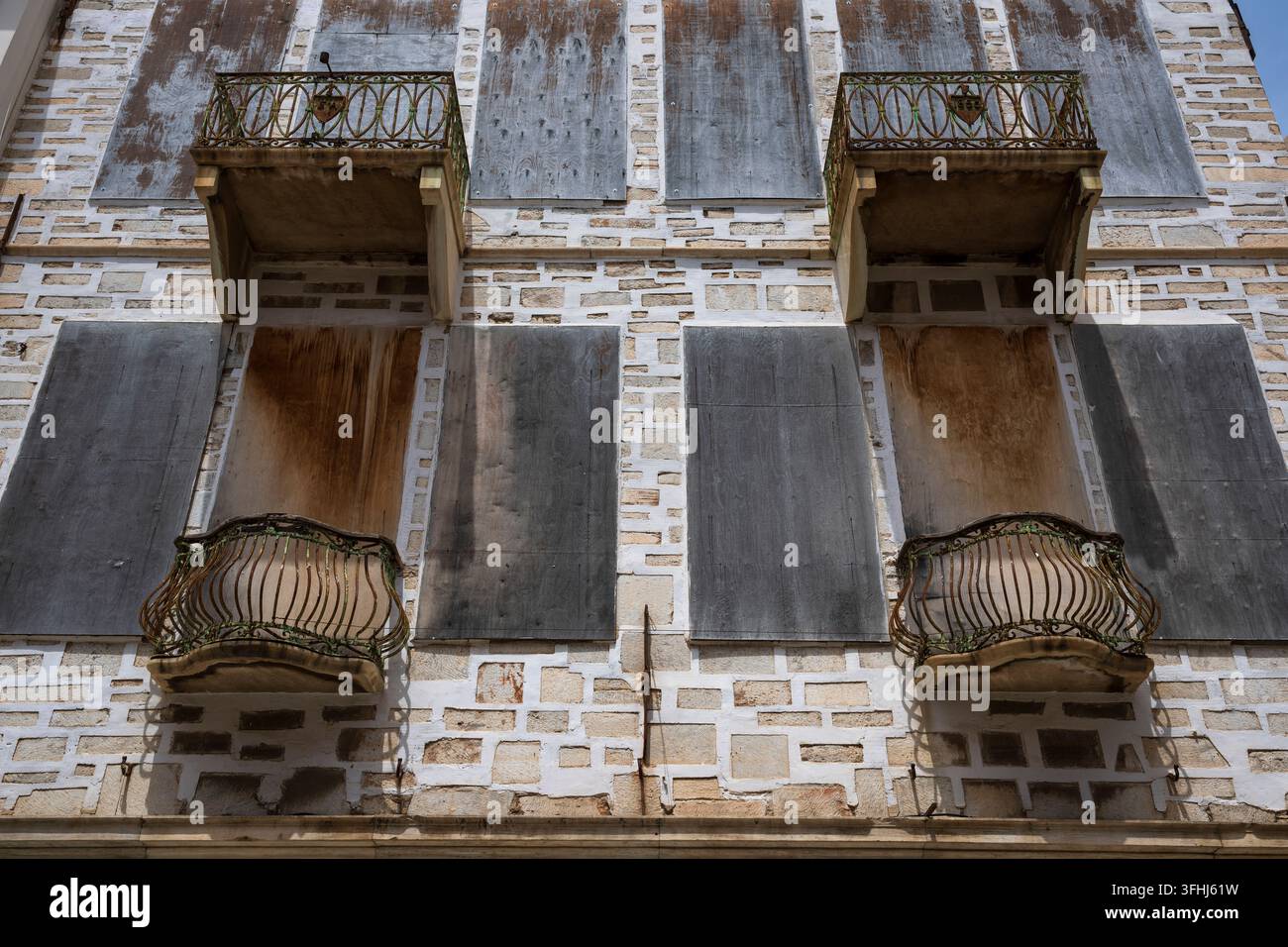 Weathered balconies and shuttered windows on old building, Syros, Greece Stock Photo