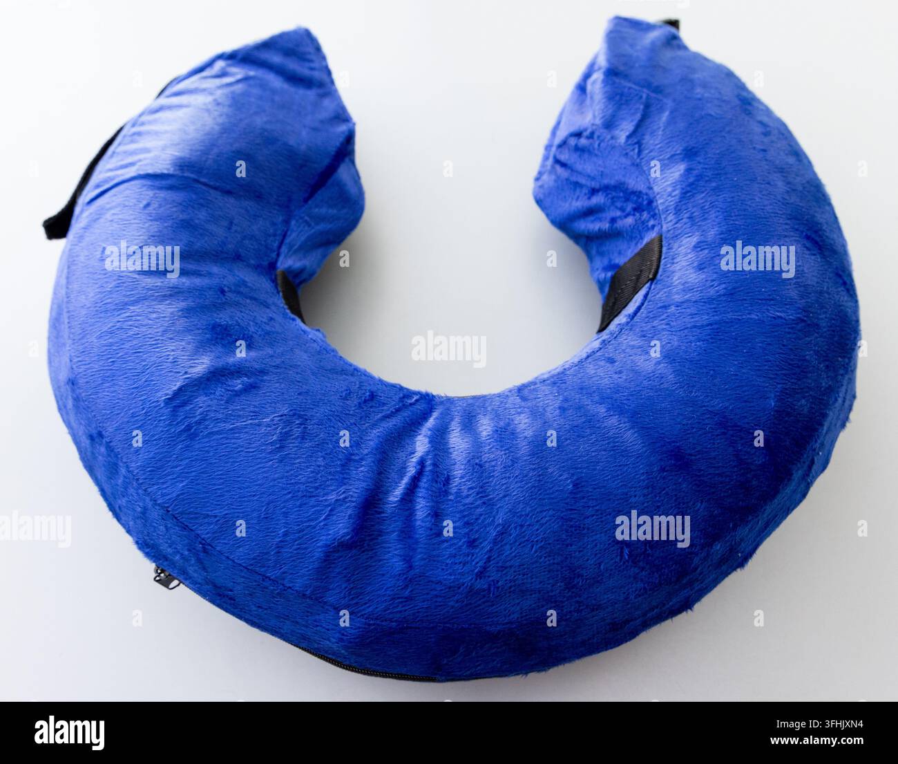 A blue plush Ushaped neck pillow rests on a white background Stock Photo