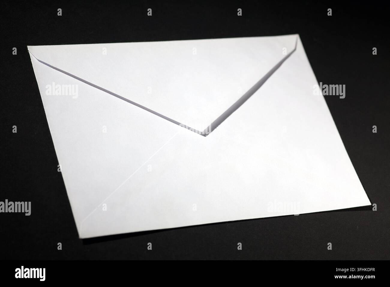 closed envelope with white spot light on black background Stock Photo