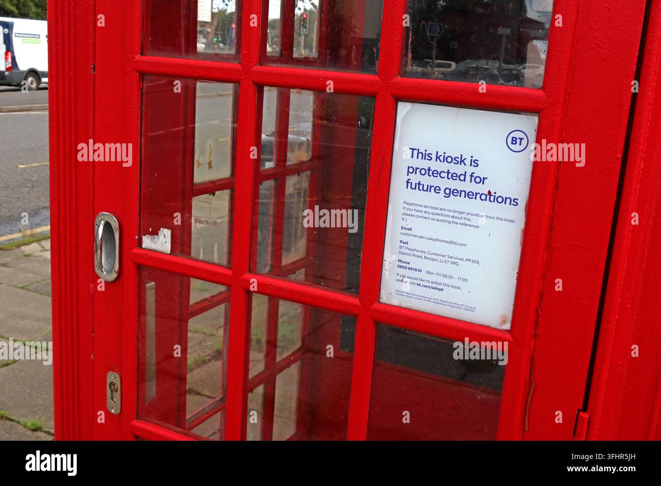 Traditional red British telephone box in Warrington with a notice stating it is protected for future generations. Stock Photo