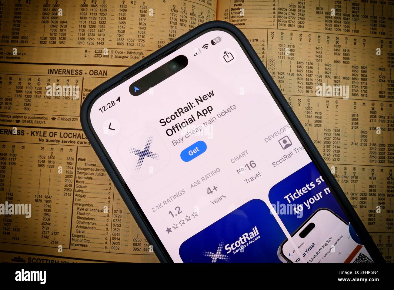 New ScotRail new 2026 mobile app displayed on a smartphone over a printed railway timetable, showing digital rail ticketing in Scotland. Stock Photo