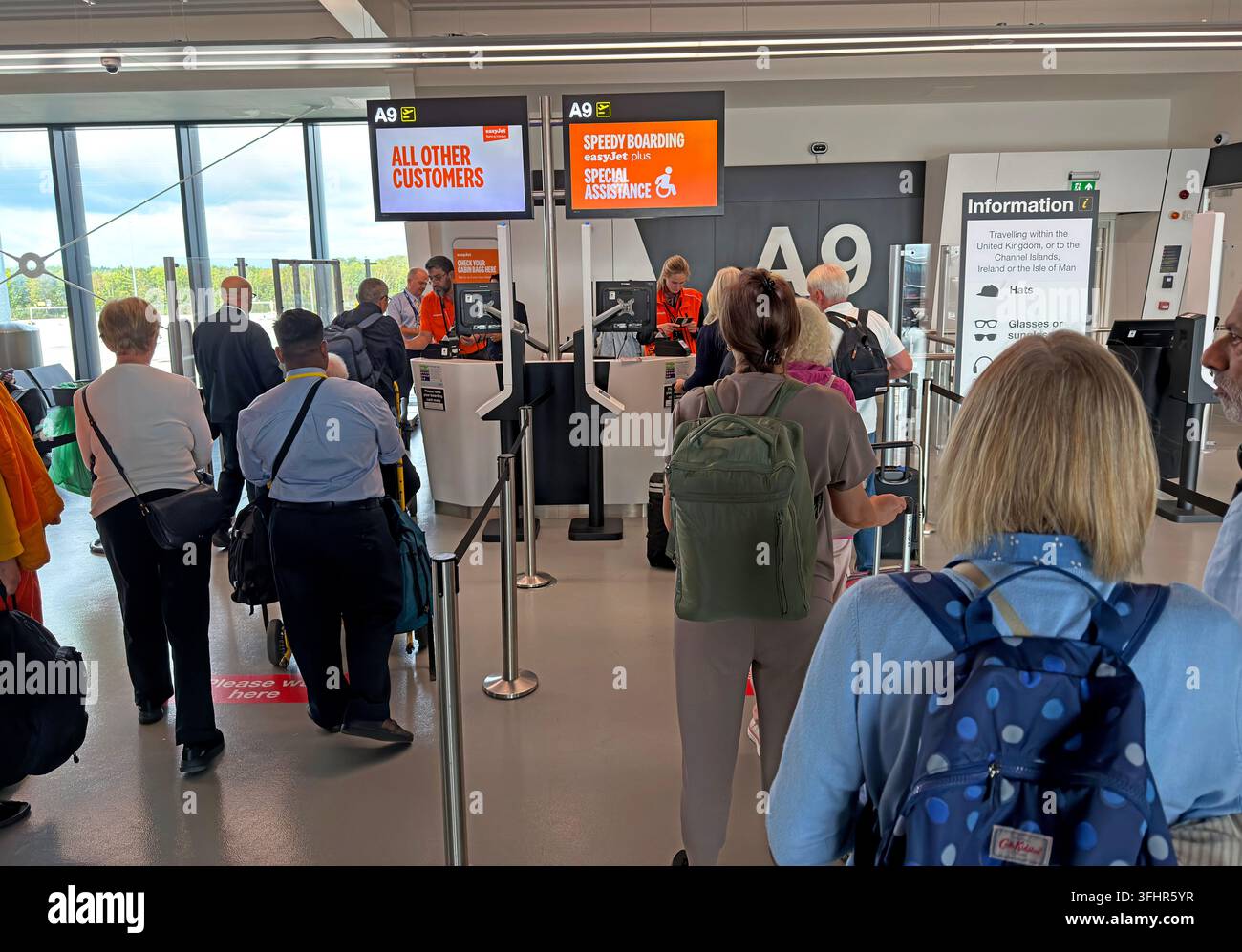 Passengers queue at an easyJet airport gate in separate Speedy Boarding and All Other Customers lanes during a busy holiday travel period. Stock Photo
