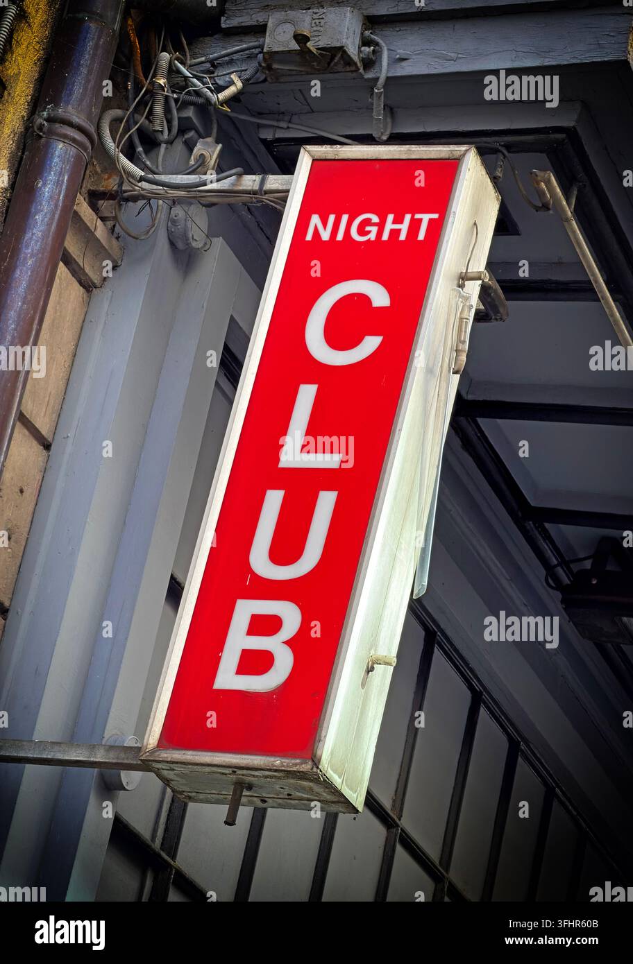 Illuminated red NIGHT CLUB sign projecting from a building at night, advertising late-night entertainment. Stock Photo