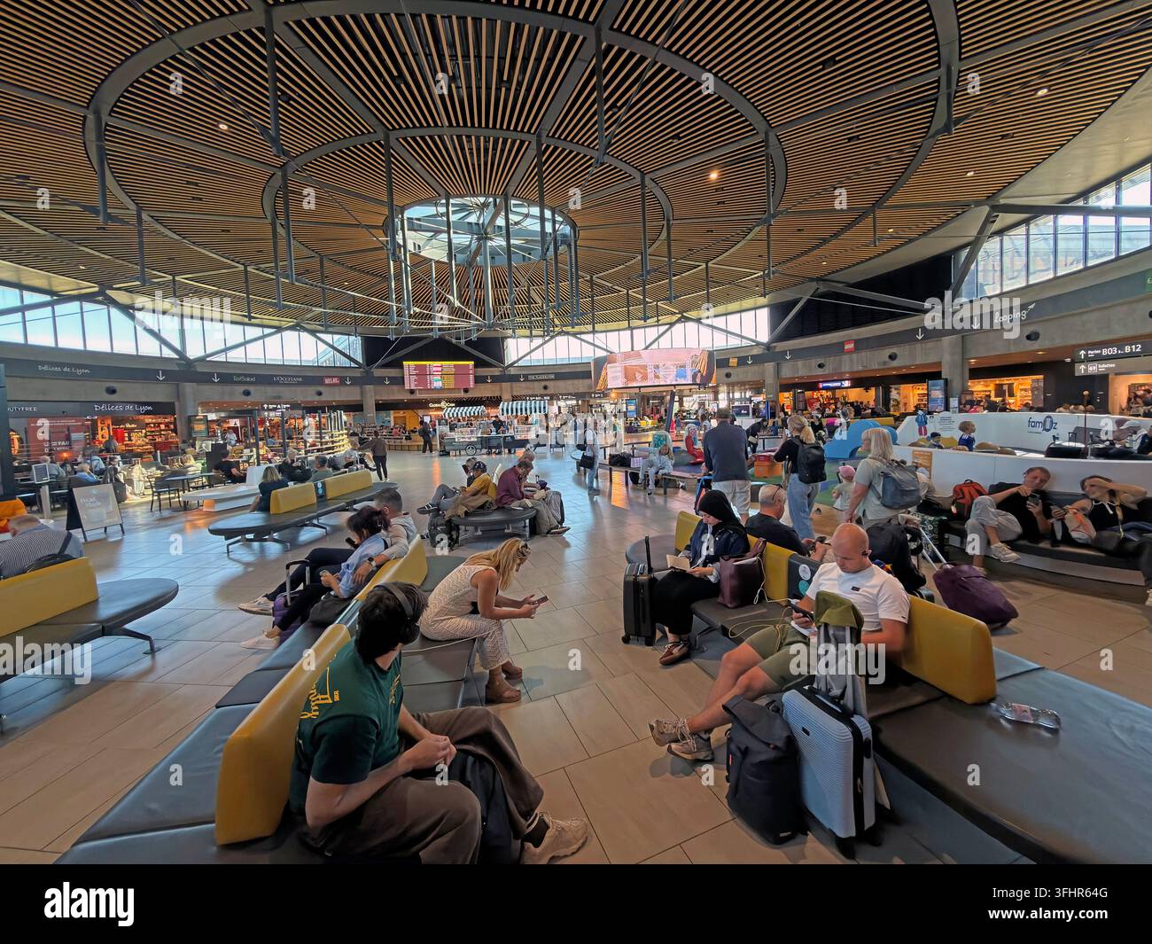 Passengers waiting in the departures lounge at Lyon-Saint Exupéry Airport, France, beneath the terminal's timber roof. Stock Photo