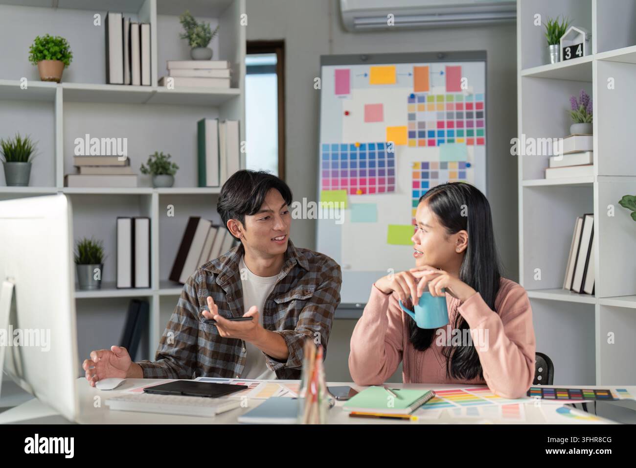 A design team collaborates on graphics projects in a vibrant office exchanging ideas and creativity. Stock Photo