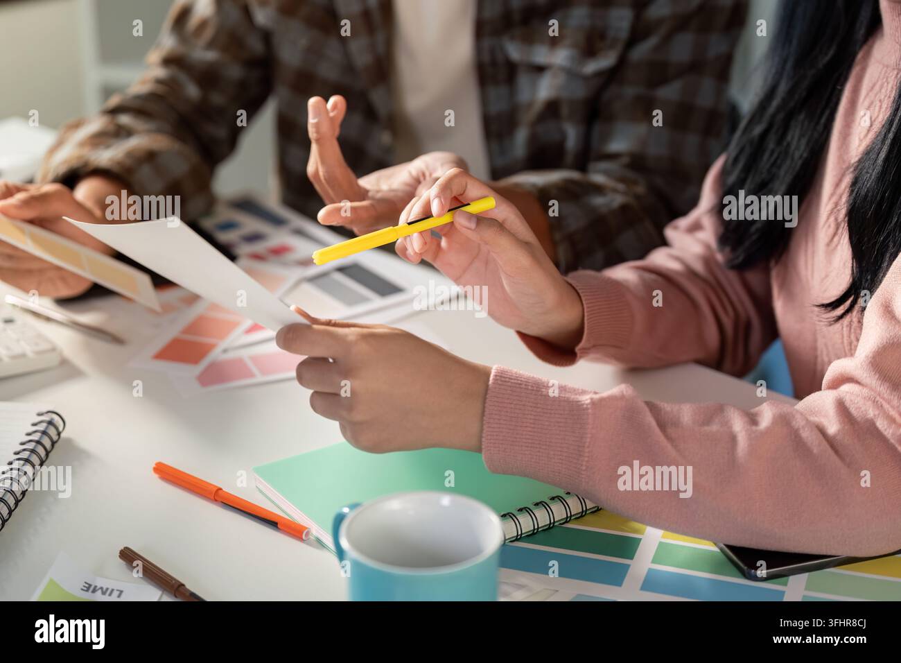 A team collaborates on graphic design projects sharing ideas and visual concepts in a modern office setting. Stock Photo