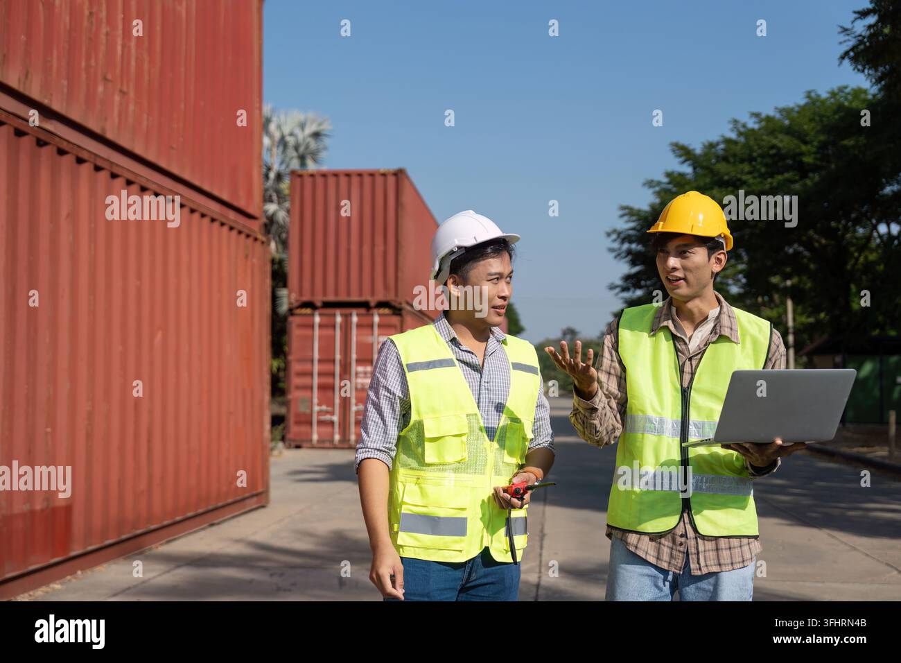 Two engineers engage in a strategic discussion about logistics while using a laptop, emphasizing modern planning techniques. Stock Photo
