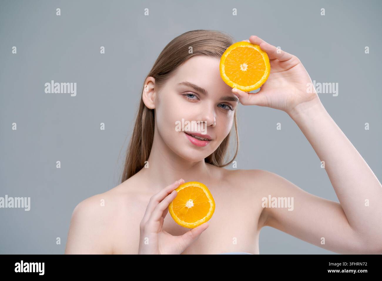 A woman is holding two oranges in her hands and smiling Stock Photo