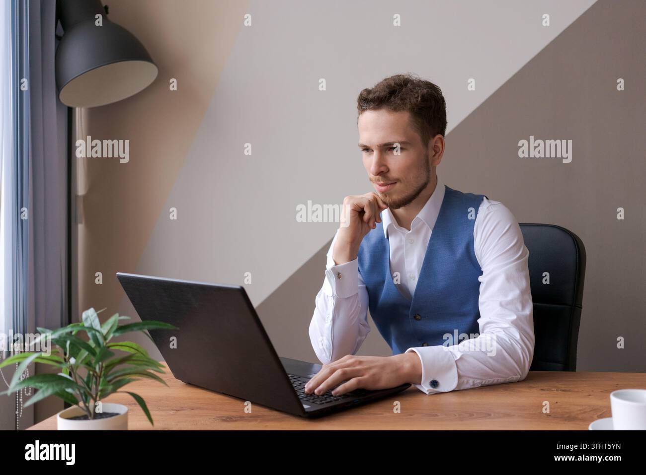 Businessman thinking about online project, looking at laptop at workplace Stock Photo