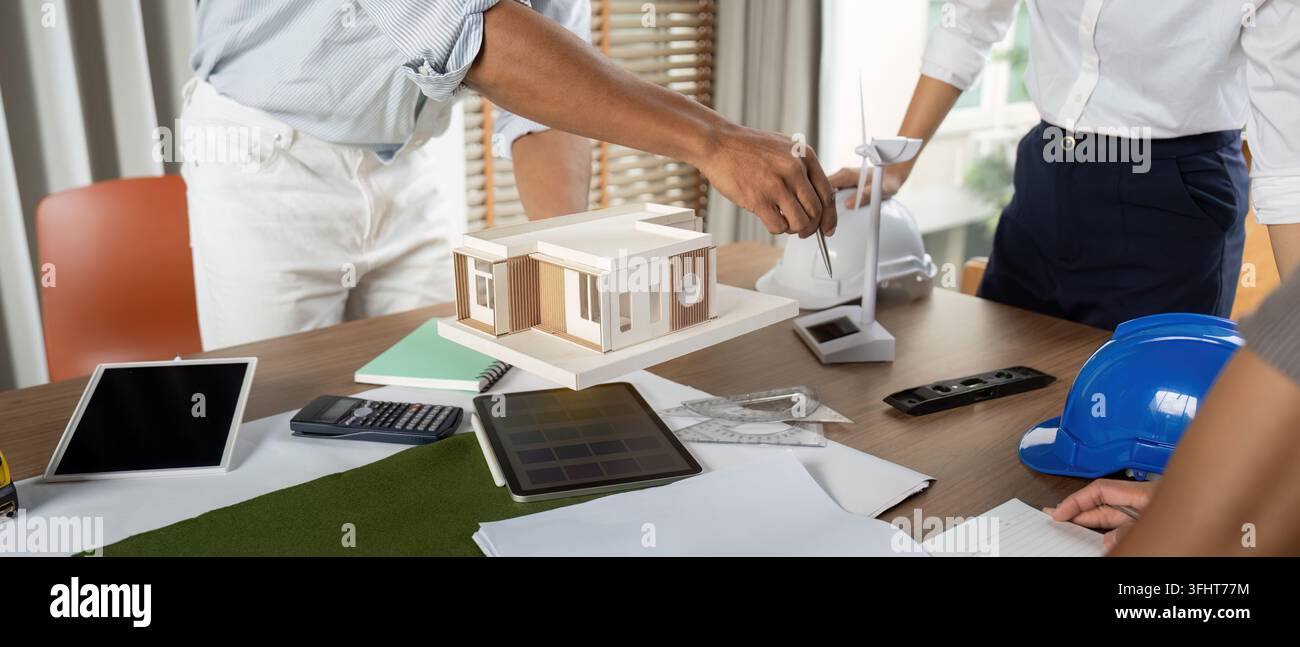 Engineers working at their workstation, skillfully finalizing innovative project designs using high-tech tools and models focused on sustainability. Stock Photo