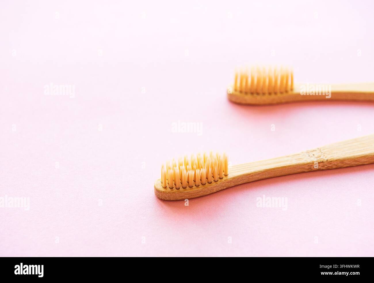 Bamboo toothbrushes on light pink background Stock Photo