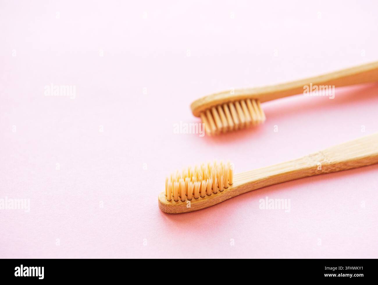 Bamboo toothbrushes on light pink background Stock Photo