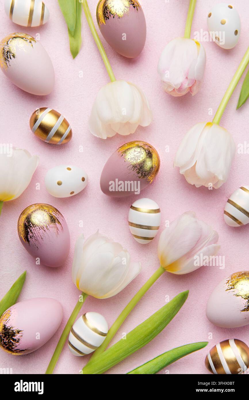 Easter golden eggs and pink tulips on pink background. Stock Photo