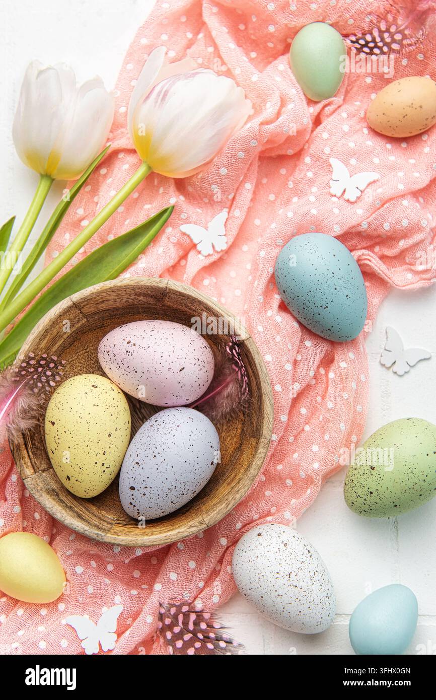 Easter background with colorful eggs in bowl and pink tulips Stock Photo