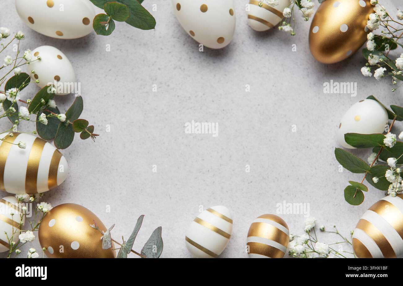 Easter eggs with gold and white decorations forming a frame on a gray background Stock Photo