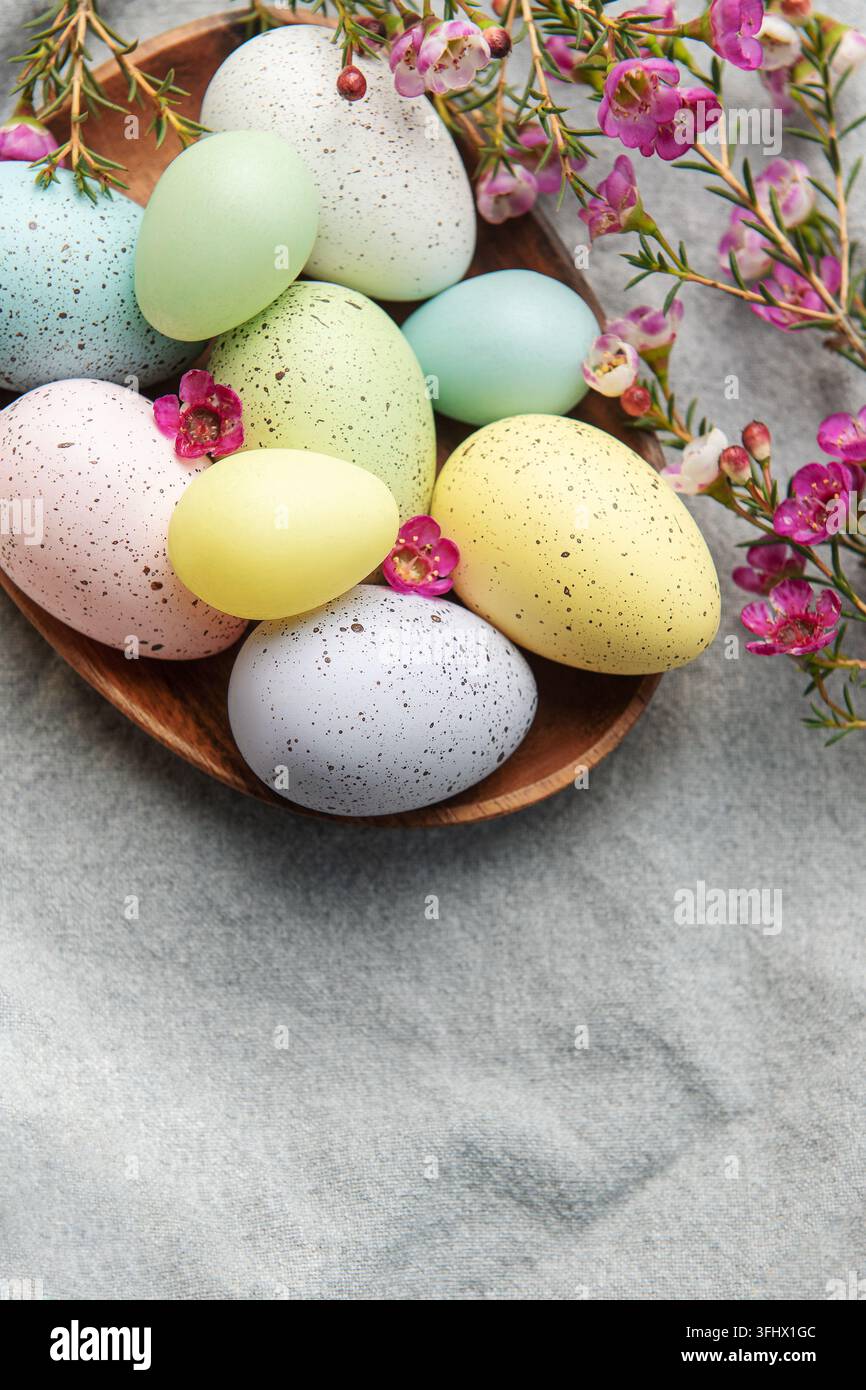 Easter decor. Colored Easter eggs on a wooden plate on the table. Stock Photo