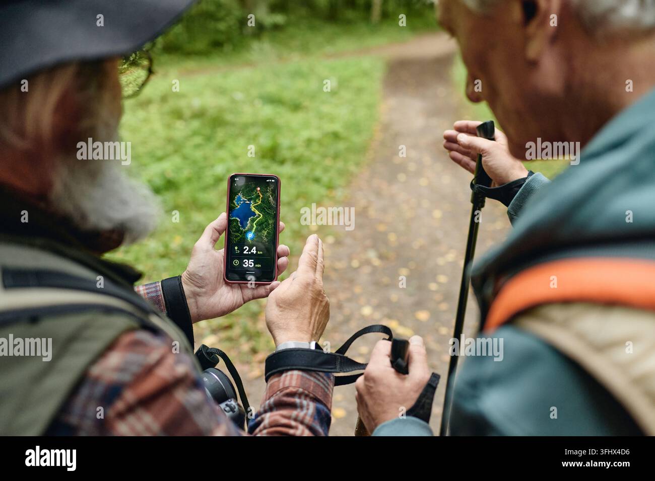 Senior Men Using Navigation Map App on Smartphone While Hiking Stock Photo