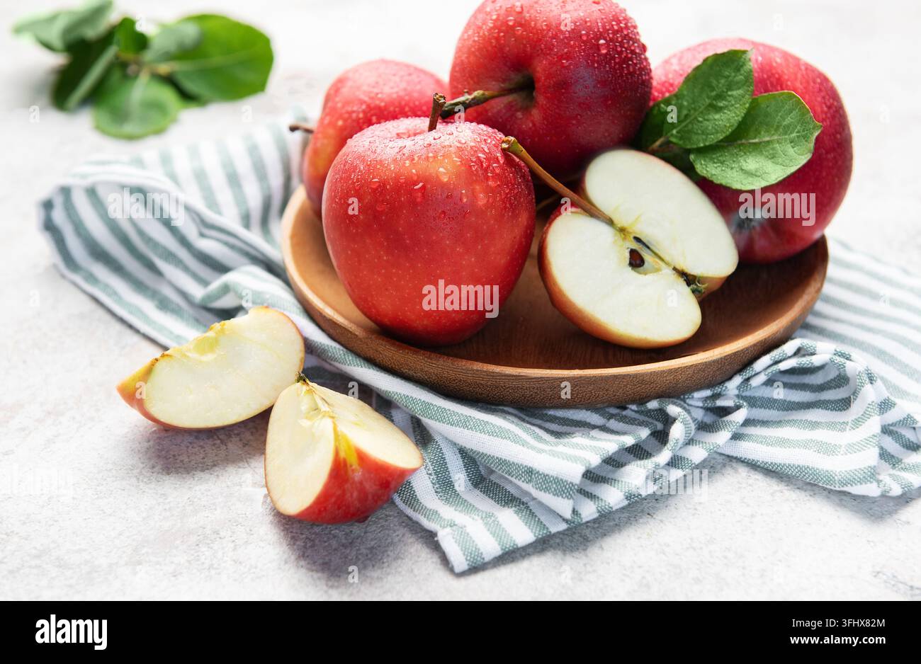 Fresh red apples in wooden bowl with slices Stock Photo