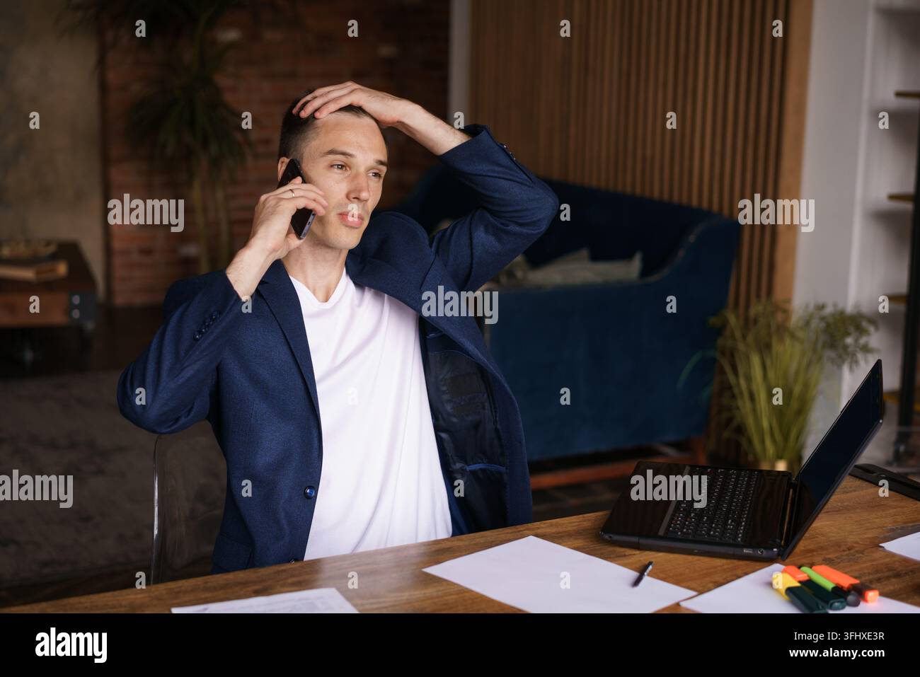 Very busy. Confident successful man in jacket working on laptop and talking Stock Photo