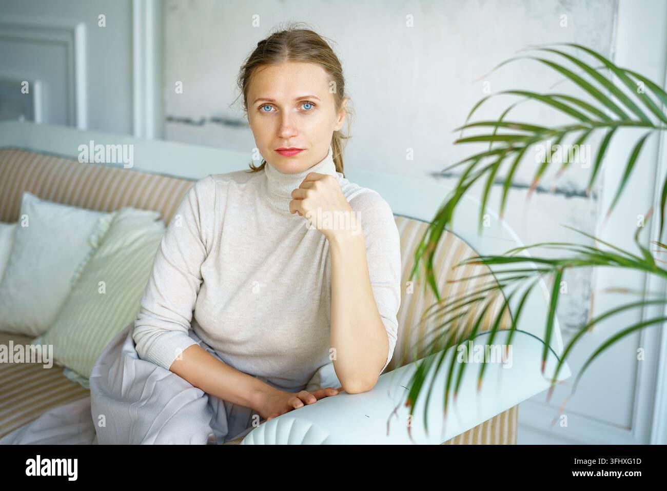 Portrait of a beautiful woman sitting on a sofa in a bright room Stock Photo