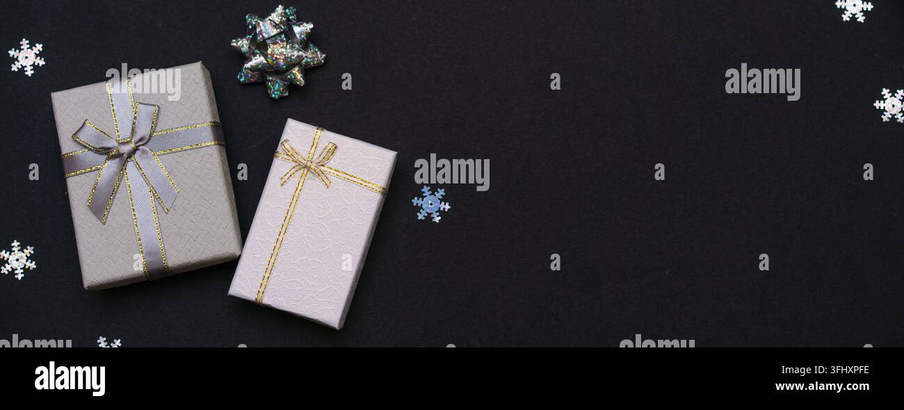 Gift boxes and snowflakes on dark paper black background. Christmas gift. Stock Photo