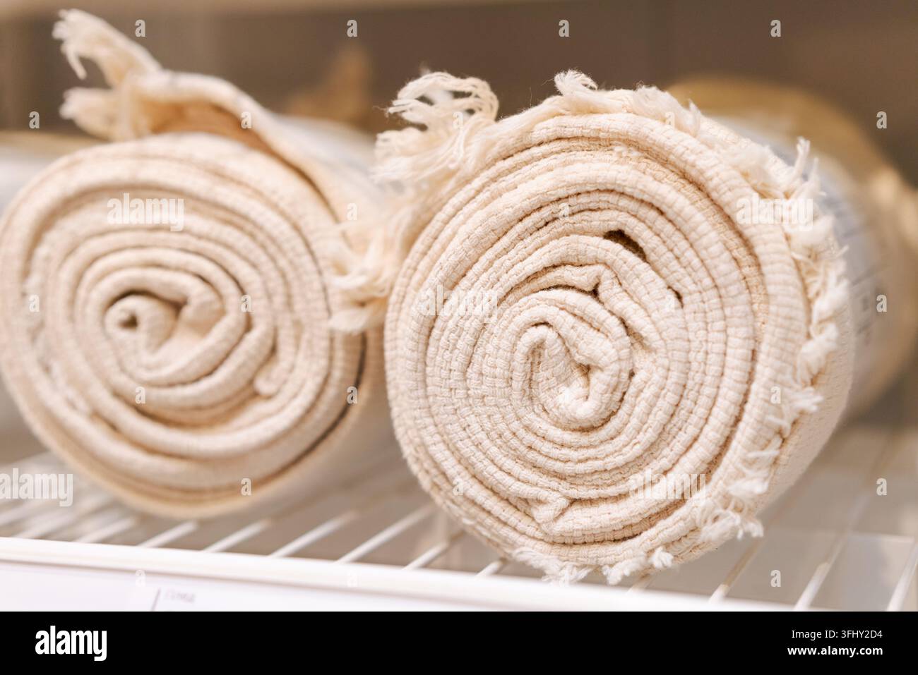 Two white towels are rolled up and placed on a shelf Stock Photo