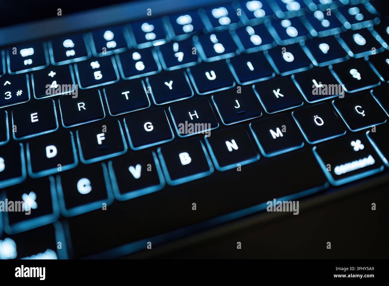 Blue illuminated laptop keyboard representing technology, programming, cybersecurity and digital communication Stock Photo