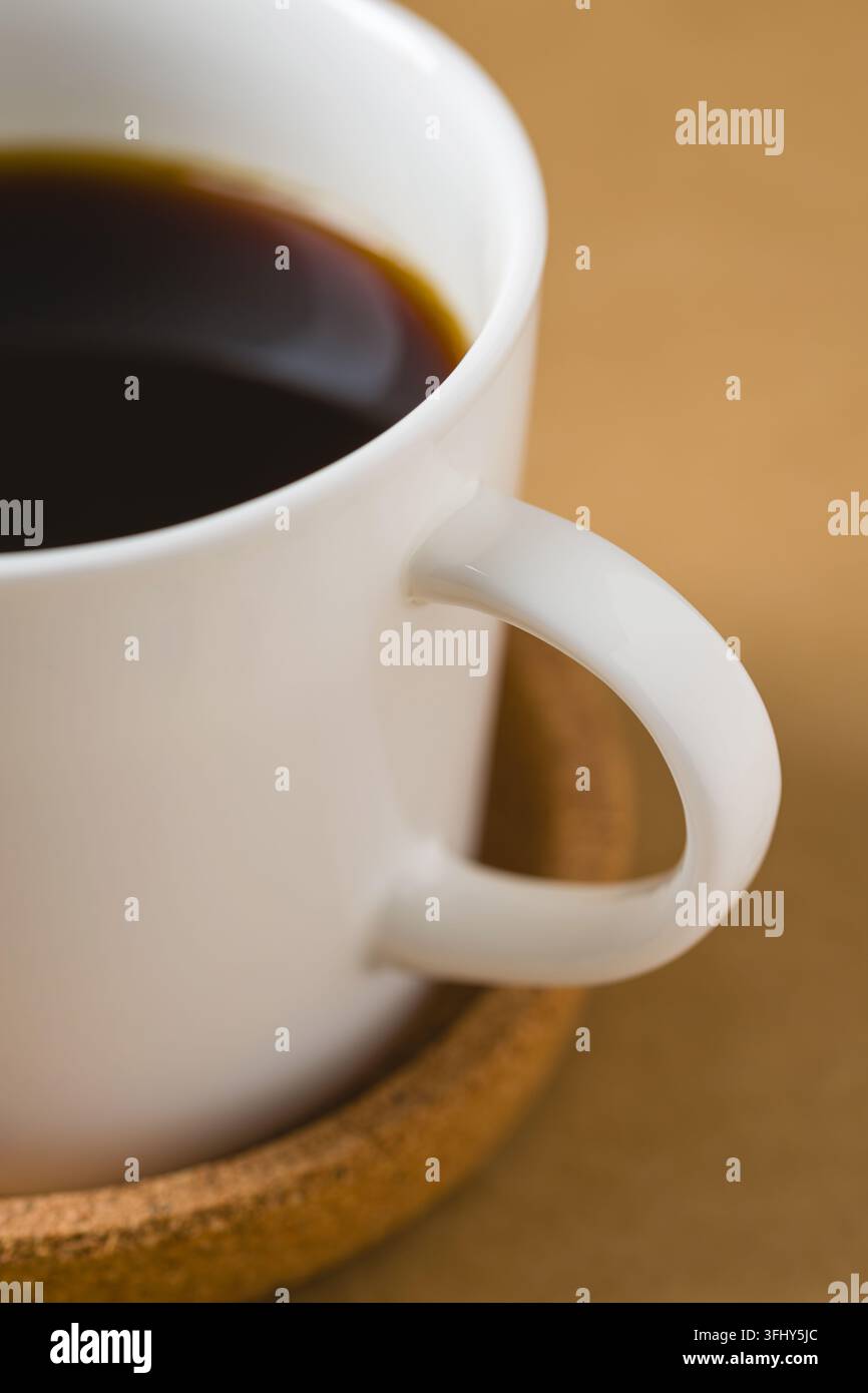 Close-up detail of black coffee in white ceramic cup and coaster Stock Photo