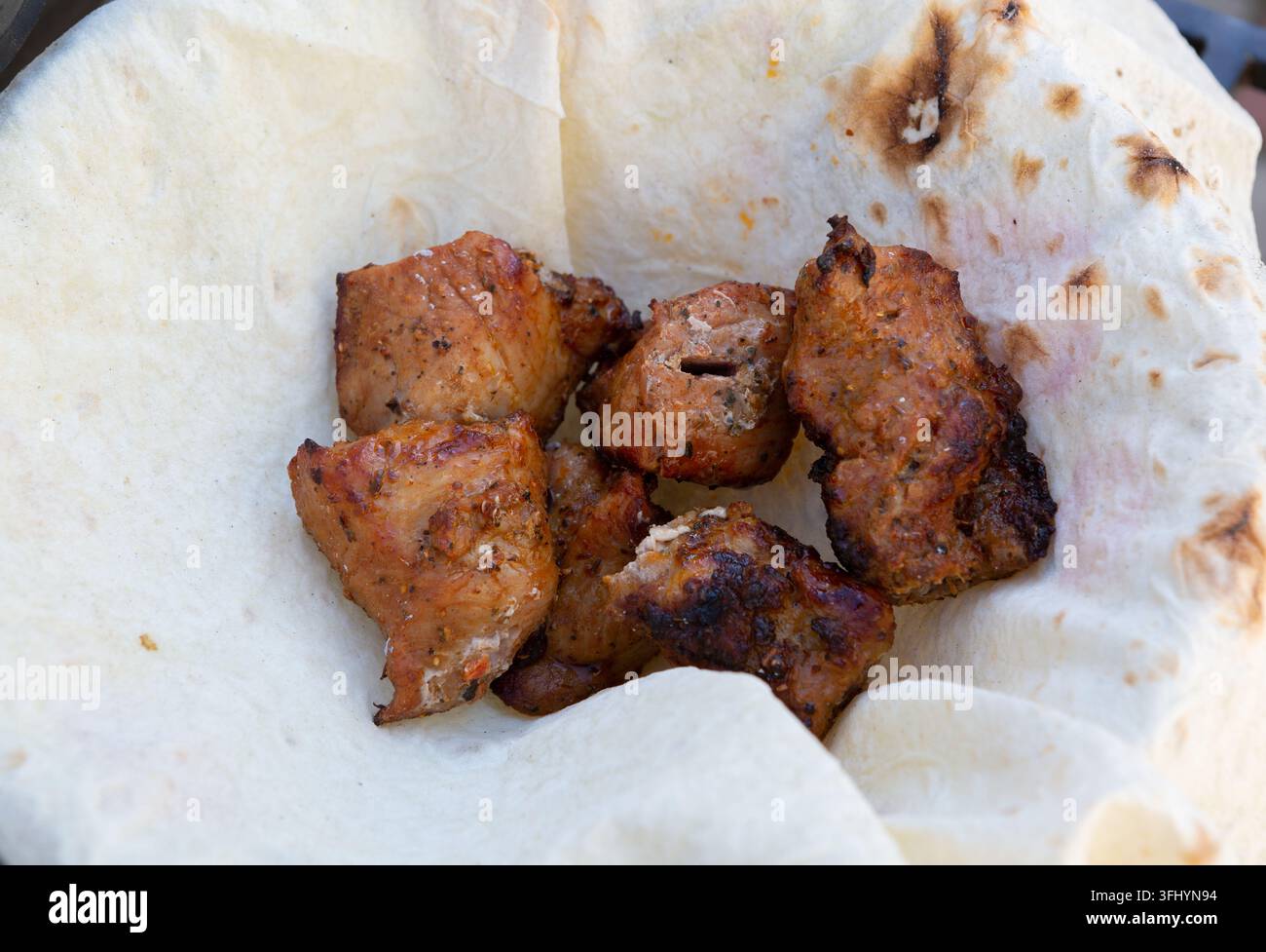 Charcoal-grilled pieces of meat lay in pita bread Stock Photo