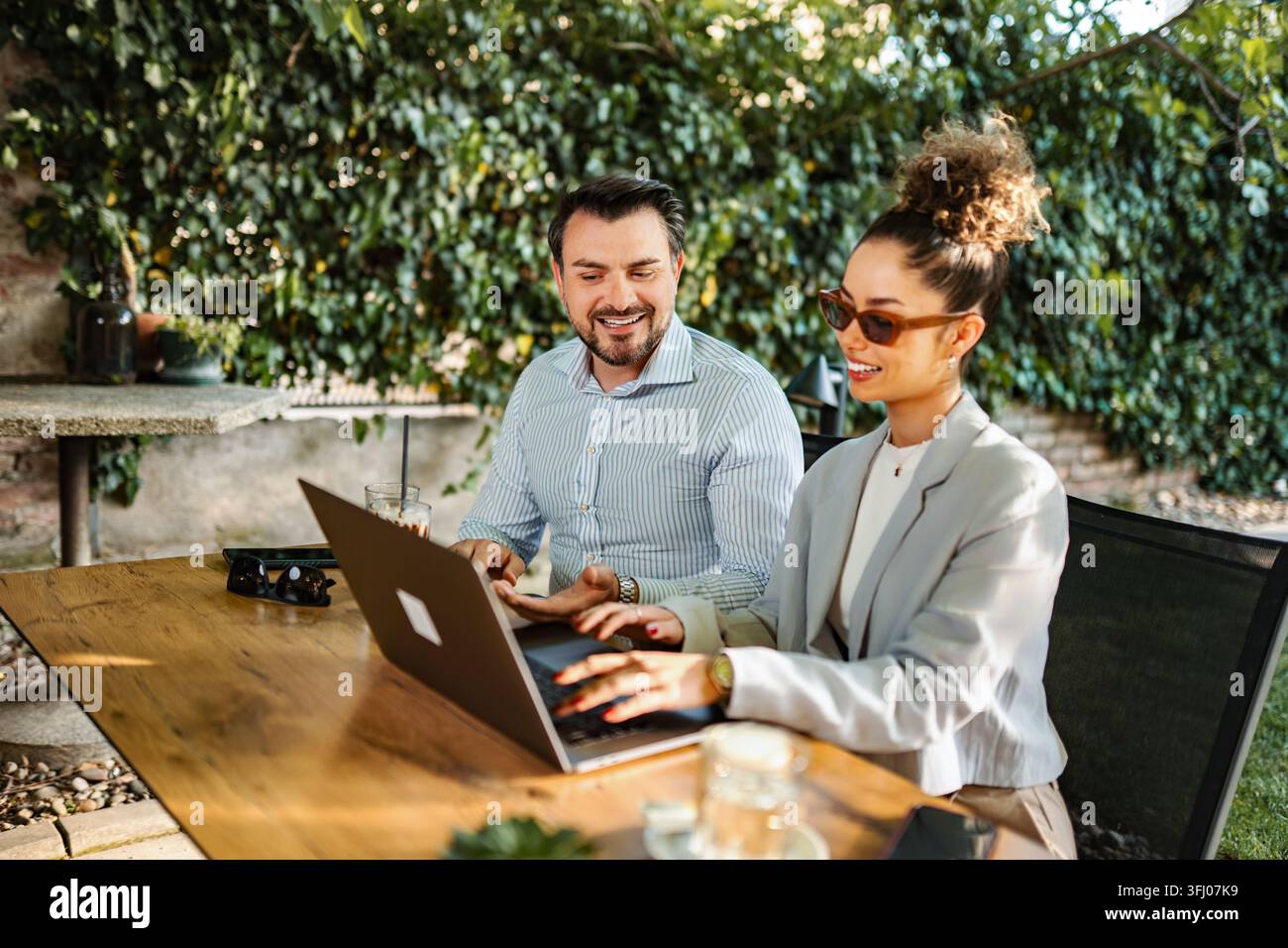 Colleagues collaborating on laptop while working remotely outdoors Stock Photo
