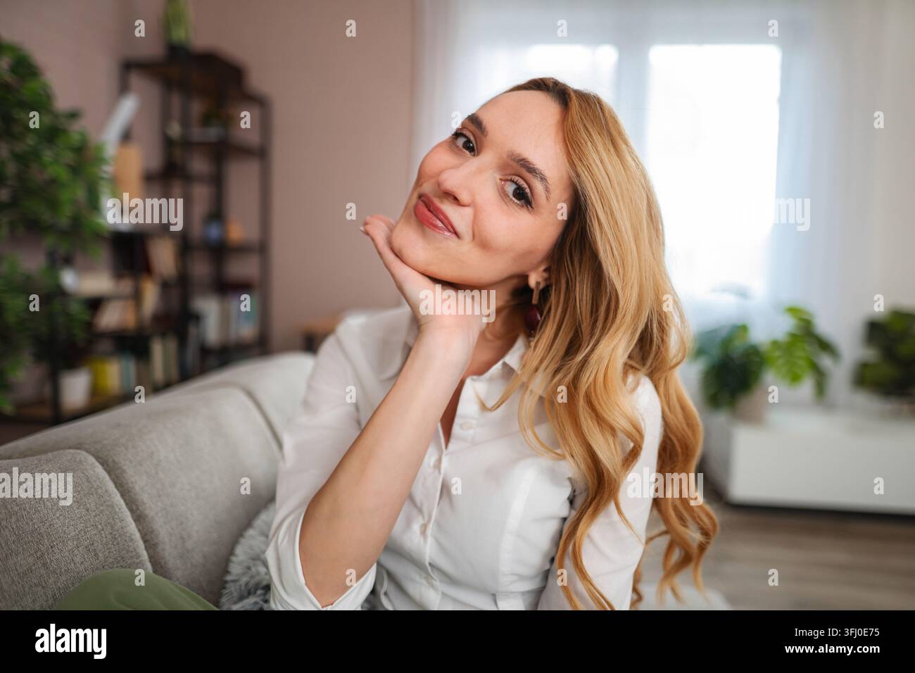 Woman smiling and relaxing on sofa at home Stock Photo