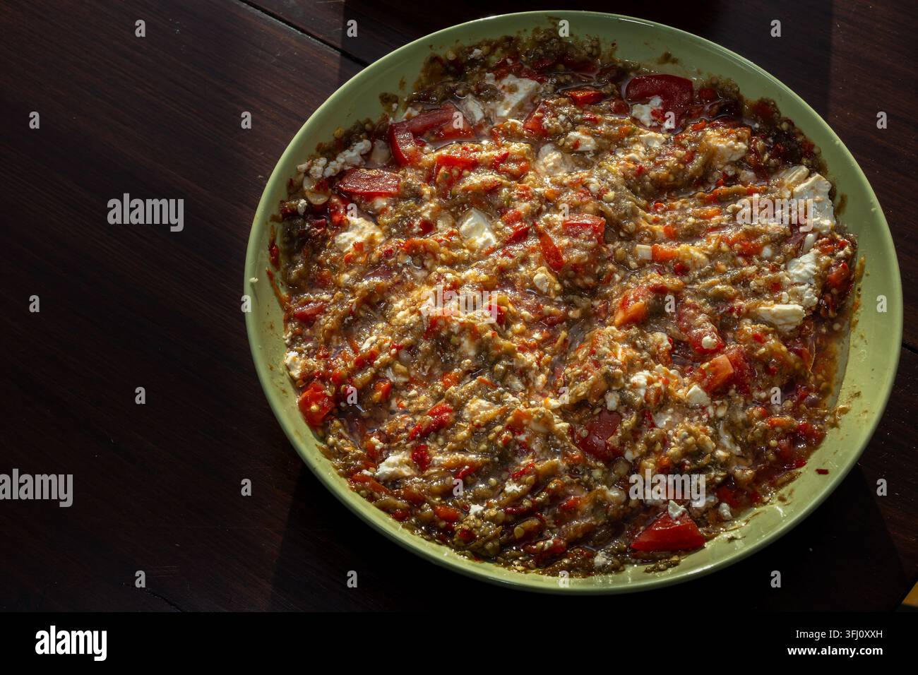 homemade bell pepper and eggplant salad served in a bowl with fresh vegetables and cheese, prepared as a traditional healthy side dish. Stock Photo