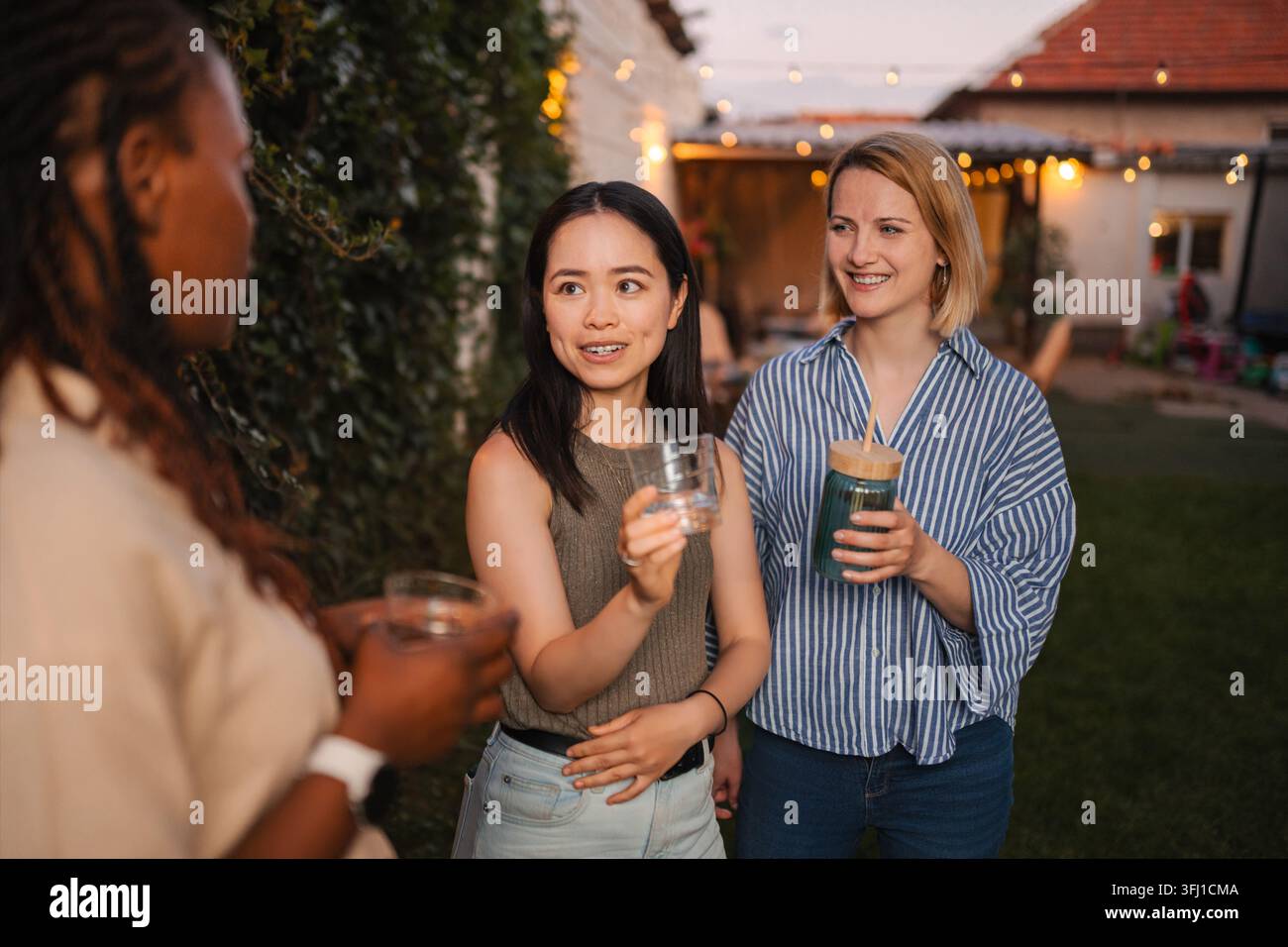 Multi ethnic women friends enjoying backyard party conversation Stock Photo