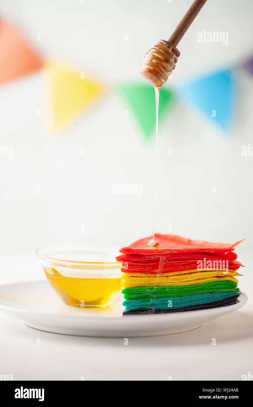 Rainbow Cake Crepe on white plate. Rainbow as symbol of inclusivity, LGBT pride. Stock Photo
