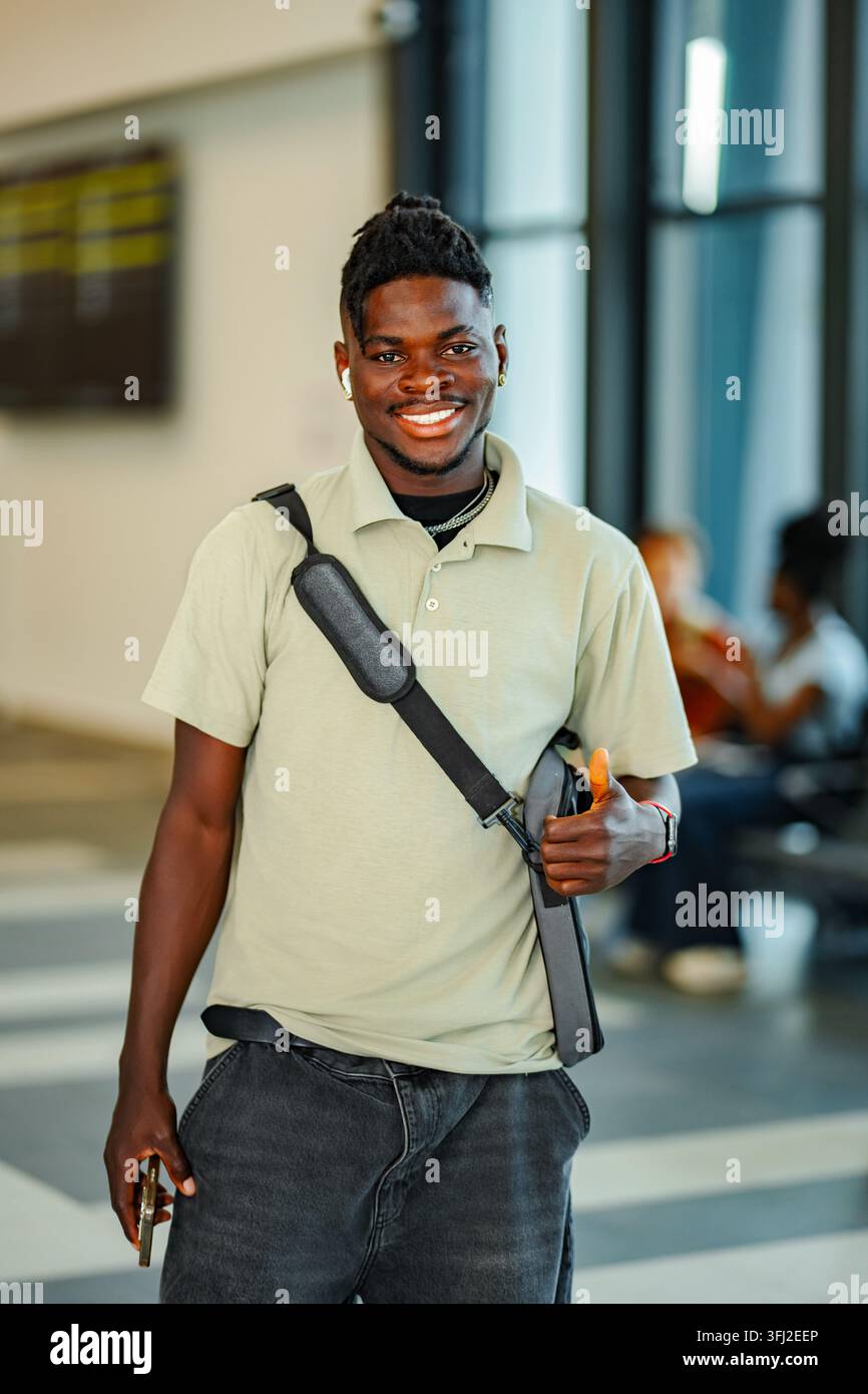 Young adult Black man giving thumbs up in airport Stock Photo
