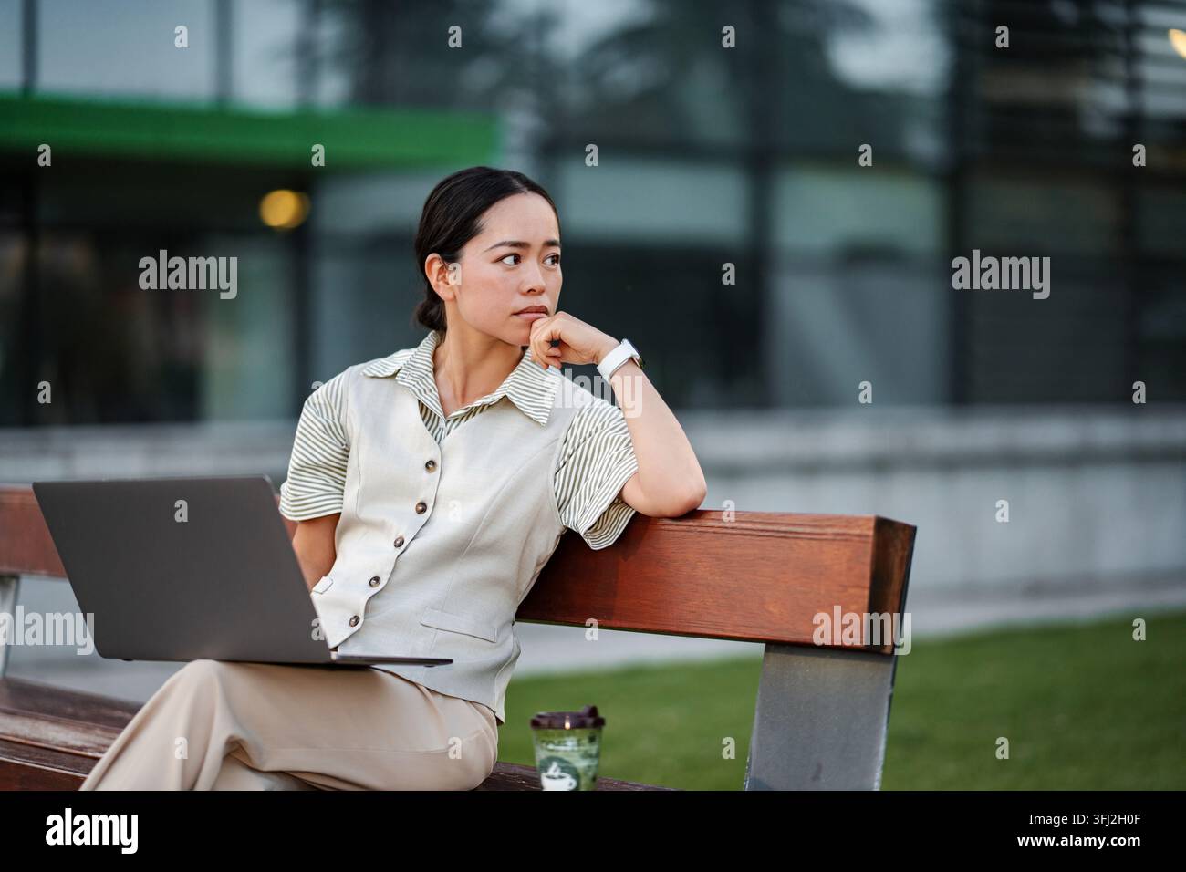 Asian businesswoman contemplating work project outdoors on bench Stock Photo