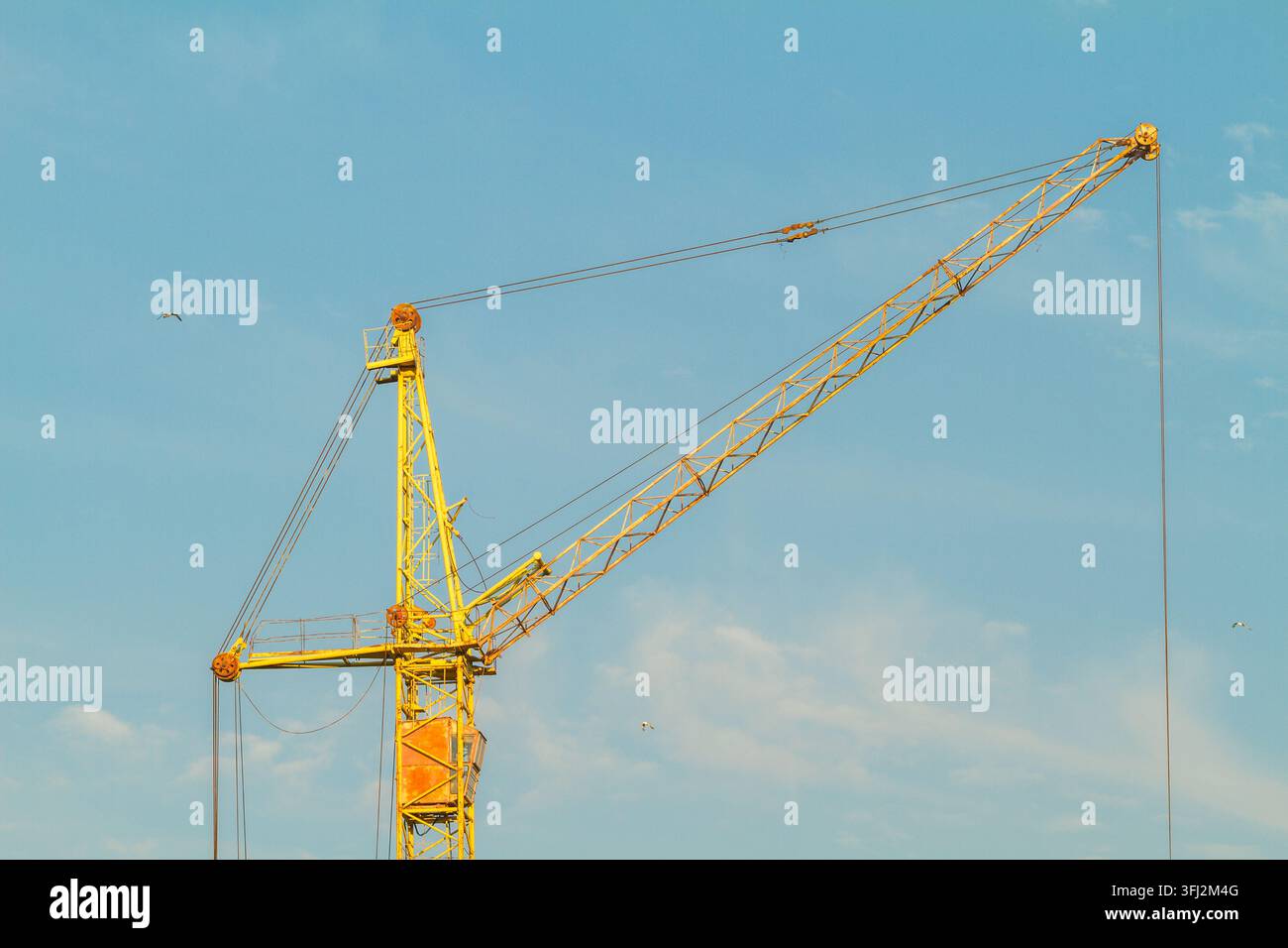 Yellow Construction Tower Crane Against a Blue Summer Sky Stock Photo