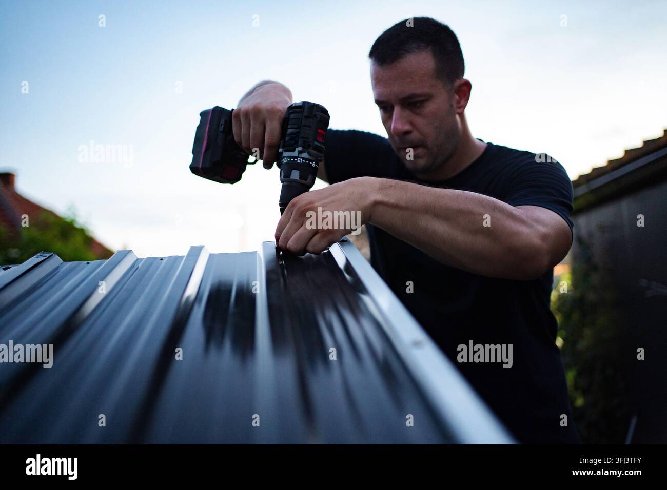 Man drilling into a metal panel, working on a construction project Stock Photo